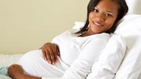 Pregnant woman smiling, lying on bed